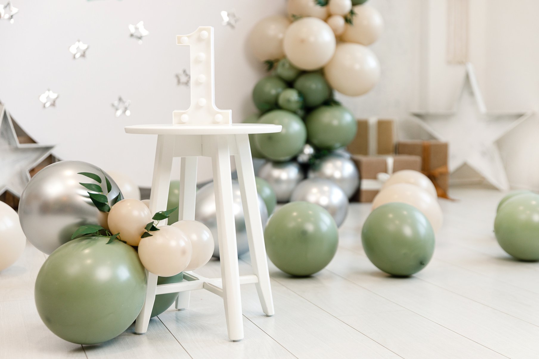 Birthday decorations - gifts, toys, balloons, garland and number for little baby party event on a white wall background.